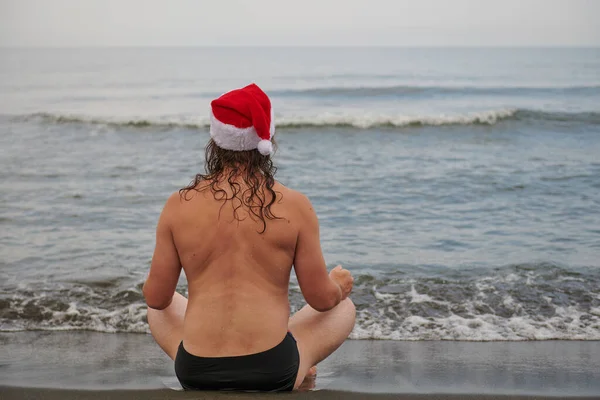 Un uomo che indossa un cappello da Babbo Natale al mare — Foto Stock