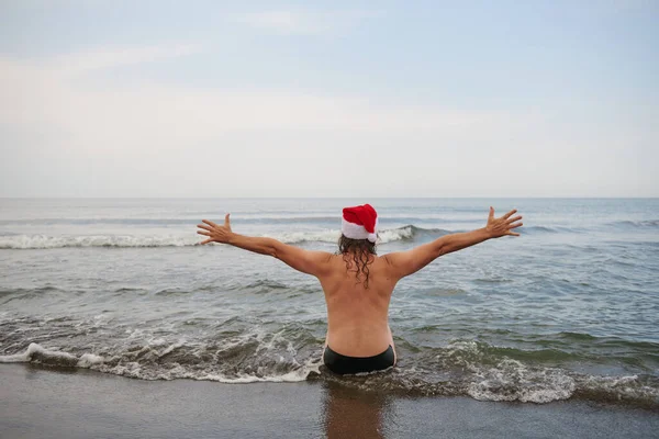 바다에서 산타 클로스 모자를 쓰고 있는 남자 — 스톡 사진