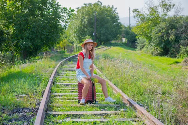 One tourist sits on the railroad on a suitcase — Stock Photo, Image