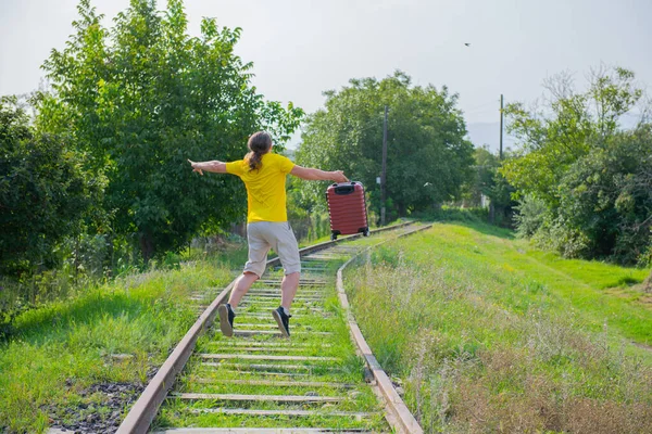 One man in yellow with a suitcase jumps on the railroad — Stock Photo, Image