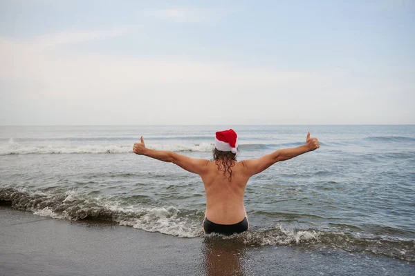 바다에서 산타 클로스 모자를 쓰고 있는 남자 — 스톡 사진
