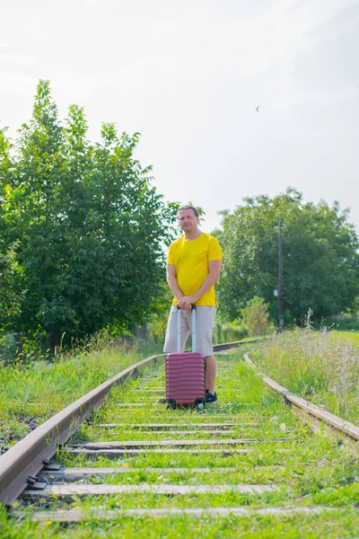 Barna férfi egy bőrönddel sétál a vasúton — Stock Fotó