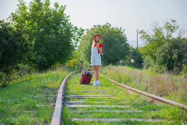 Mischievous traveler with flowers and a suitcase on the railroad — Stock Photo, Image