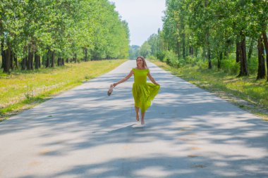 Bir kadın yolda elbisesiyle koşuyor.