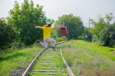 Elinde bavuluyla demiryoluna atlayan deli bir adam.