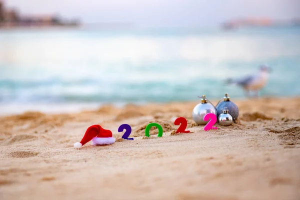 Капелюх Санта Клауса 2022 числа лежать на піску поруч з подарунками. — стокове фото