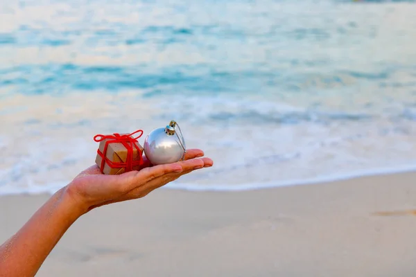 Kerstcadeau en speelgoed in de hand op de zee — Stockfoto