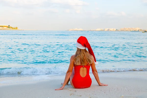Girl on the beach in a bikini and a santa hat — Stockfoto