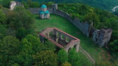 Dağlardaki eski bir kalenin kalıntıları yeşil ağaçlar.