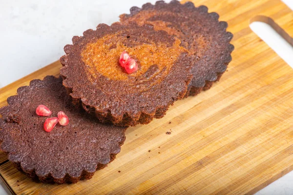 Tres pequeños pasteles de cacao con granada están sobre la mesa —  Fotos de Stock
