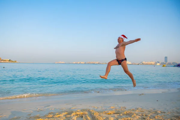 Hombre saltando en un sombrero de Año Nuevo en la playa — Foto de Stock