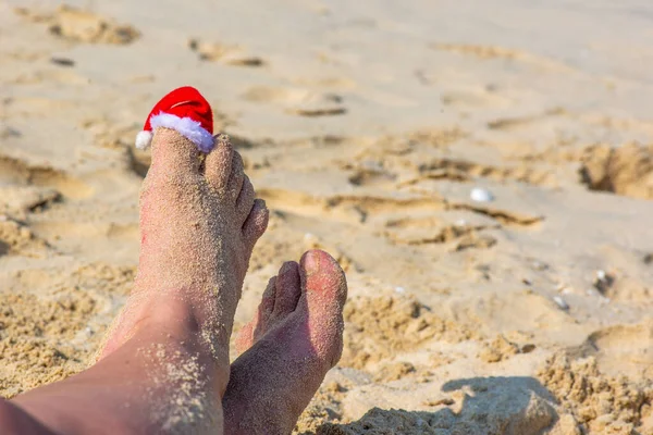 Santas hat is on his feet in the sand — 图库照片