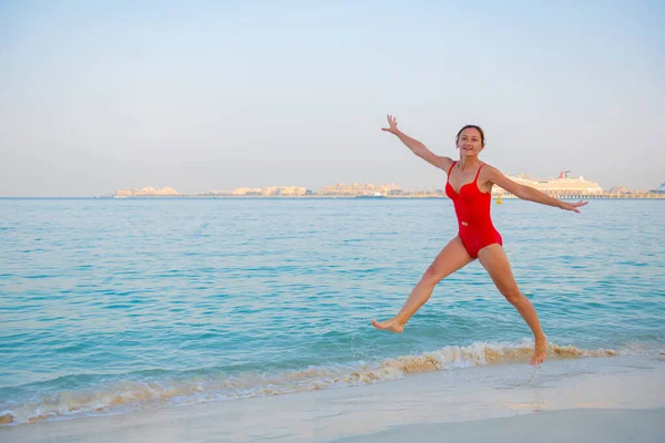 Beautiful girl in a swimsuit jumping on the beach — 스톡 사진