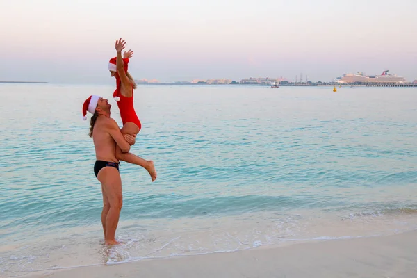 In the sea, a girl and a guy in their arms holds in a New Years hat — 스톡 사진