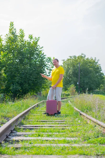Homem solitário com uma mala andando na estrada de ferro — Fotografia de Stock