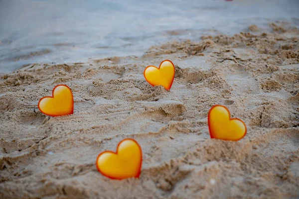 Quattro cuori gialli nella sabbia stanno sul mare — Foto Stock