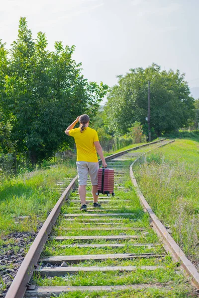Um viajante com uma mala está andando na estrada de ferro — Fotografia de Stock