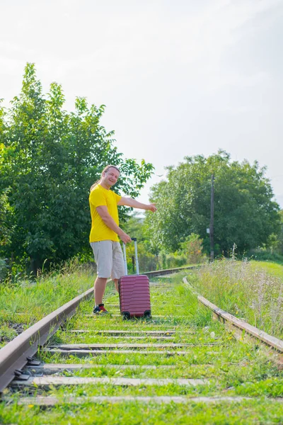 Egy vidám férfi egy bőrönddel sétál a vasúton. — Stock Fotó