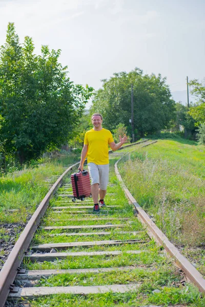 Boldog turista egy bőrönddel sétálva a vasúton — Stock Fotó