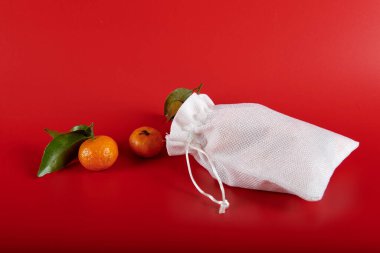 Kırmızı arka planda, mandalinalı beyaz bir çanta.