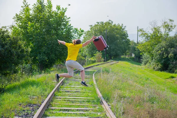Elinde bavuluyla demiryoluna atlayan neşeli bir adam. — Stok fotoğraf