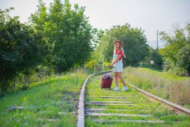 Demiryolunda çiçekli ve bavullu ilginç bir turist.