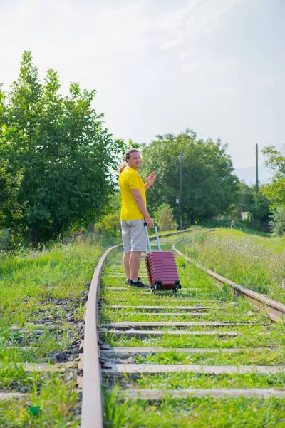 O cara caminha na estrada de ferro com uma mala — Fotografia de Stock