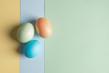 Üç renkli arkaplanda birkaç Paskalya yumurtası var.