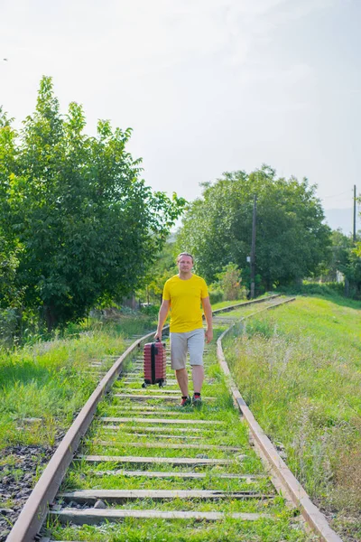 Homem feliz com mala andando na estrada de ferro — Fotografia de Stock