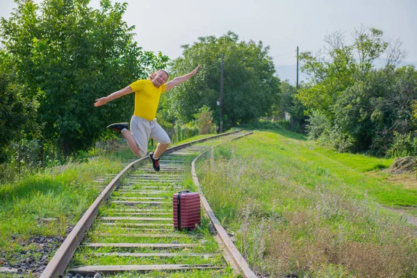 Komik yeni gelen bavuluyla demiryoluna atlıyor. — Stok fotoğraf