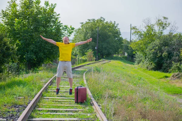 Elinde bavuluyla demiryoluna atlayan neşeli turist. — Stok fotoğraf