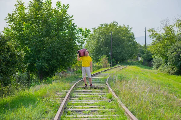 A slow man in a yellow t-shirt walks on the rails — Stock Photo, Image