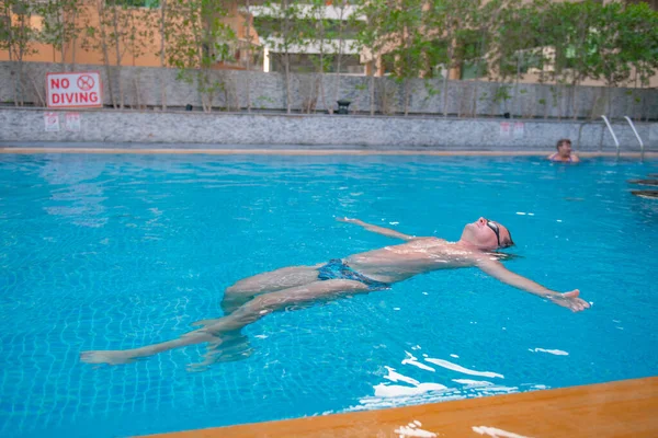 Jeune homme sur le dos nage dans la piscine — Photo