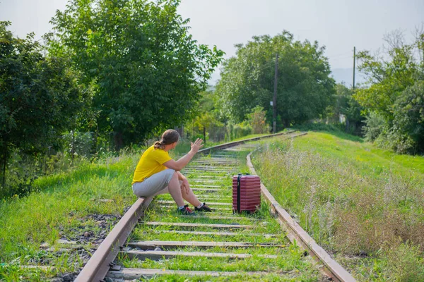 Demiryolunda kırmızı bavullu bir adam oturuyor. — Stok fotoğraf