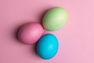 Pembe arka planda üç tane boyalı yumurta var.