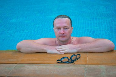 Üzgün bir adam derin bir havuzda yüzüyor.