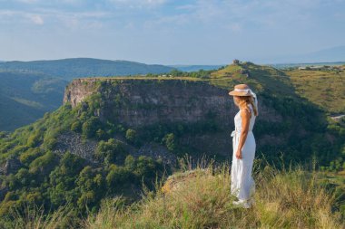 Şapkalı bir kız Georgia 'da bir kanyonun yamacında oturuyor.