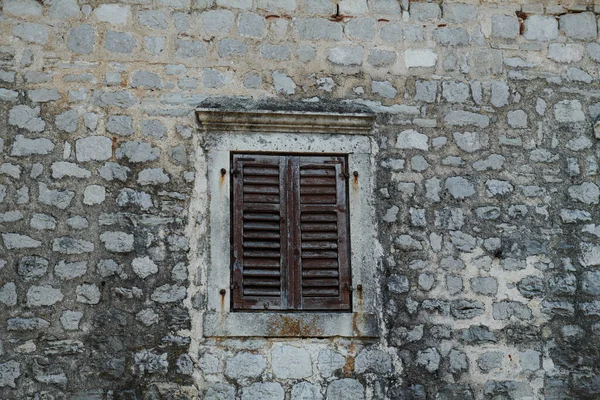 La pared de piedra es vieja y la ventana con persianas — Foto de Stock