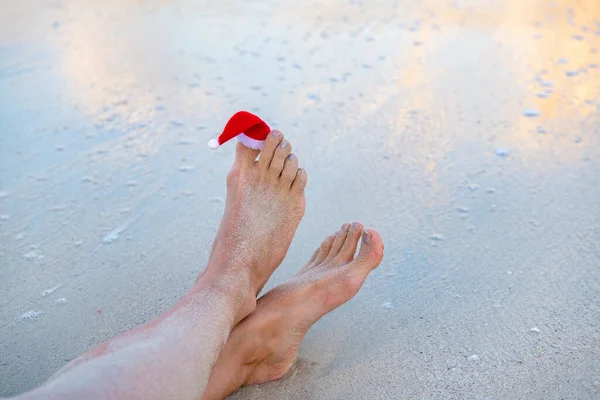 Weihnachtsmann-Mütze wird am Strand auf dem Zeh getragen — Stockfoto