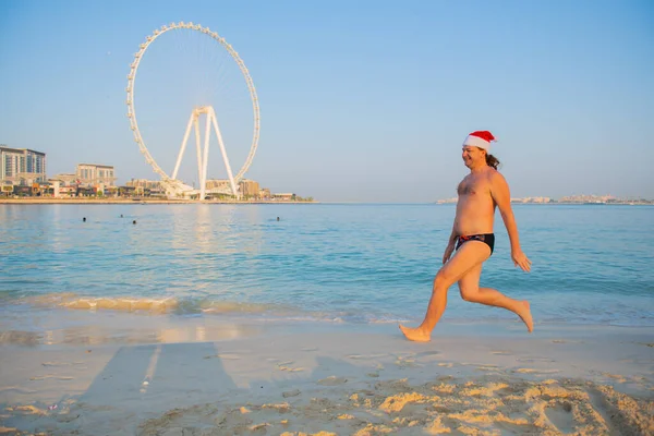 Nelle uae un giovane con un cappello da Babbo Natale che salta sulla spiaggia — Foto Stock