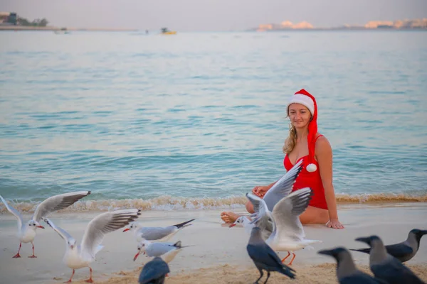 Girl in red swimwear and shanty hat sits on the beach — 스톡 사진