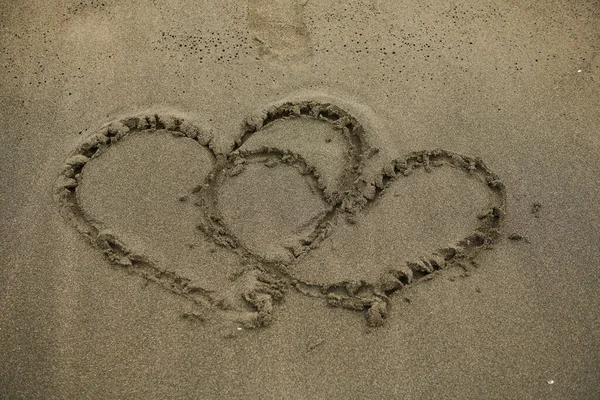 Due cuori dipinti sulla sabbia vicino al mare — Foto Stock