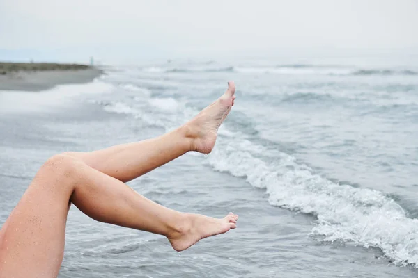 在海浪的背景下，女人的腿在空中翘起 — 图库照片