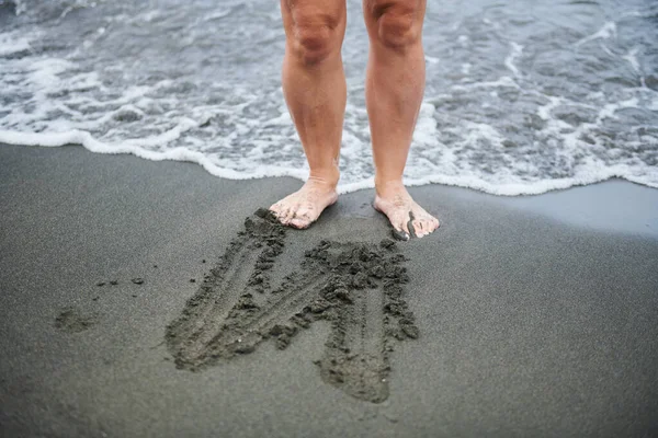 Der Buchstabe Z auf schwarzem Sand und zwei Beinen — Stockfoto