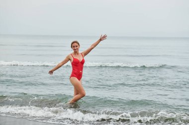 Sahilde yürüyen kırmızı mayolu kız. Yüksek kalite fotoğraf