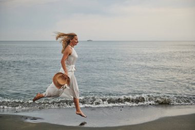 Beyaz elbiseli bir kız plajda koşuyor. Yüksek kalite fotoğraf