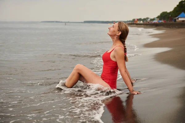 一个穿着红色泳衣的女孩躺在海边 高质量的照片 — 图库照片