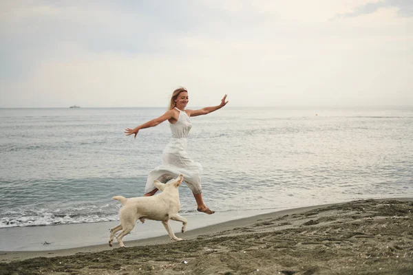 Beyazlar içinde zıplayan kız ve kumsalda köpek. Yüksek kalite fotoğraf