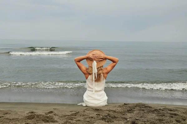 白色的衣服和帽子是给看大海的女孩的 高质量的照片 — 图库照片