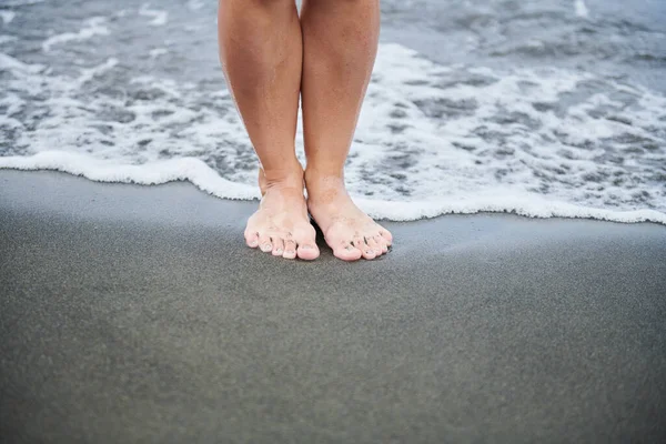 Twee Vrouwenvoeten Staan Zwart Zand Hoge Kwaliteit Foto — Stockfoto